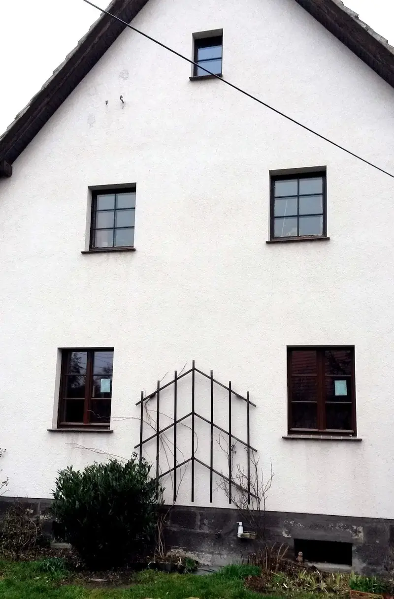 Weiße Giebelfassade mit dunklen Sprossenfenstern
