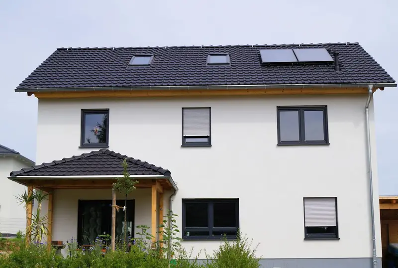 Helles Haus mit dunklen Fenstern und Satteldach